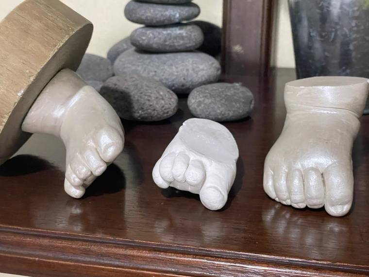 Tres esculturas en yeso de manos y pies de bebé.