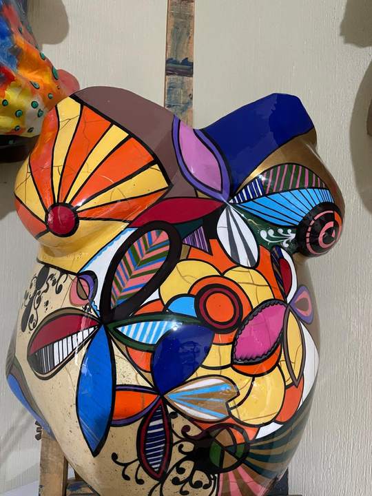 Barriga en yeso pintada con figuras geométricas de colores y detalles dorados.