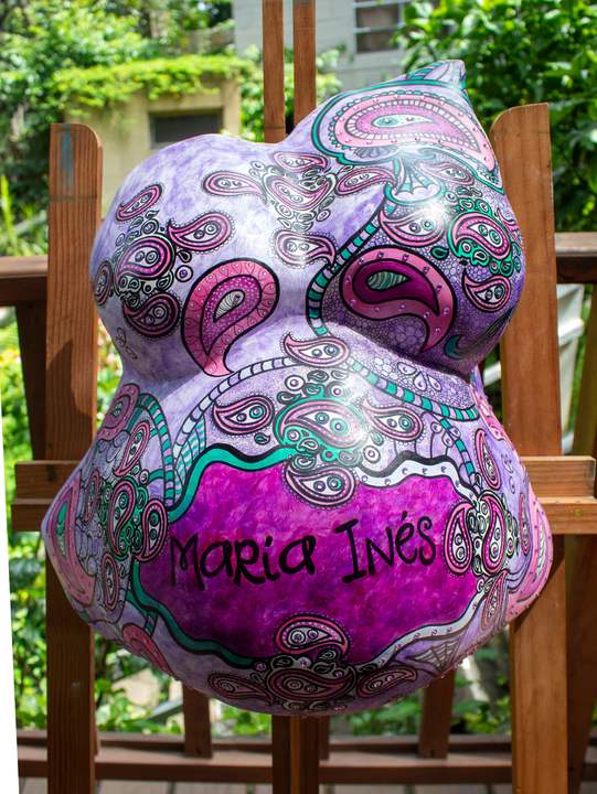 Barriga en yeso pintada en tonos morados con motivos paisley y el nombre María Inés.