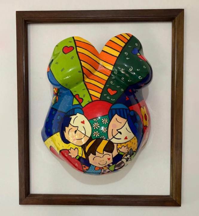 Barriga en yeso pintada con una familia, montada dentro de un marco de madera.